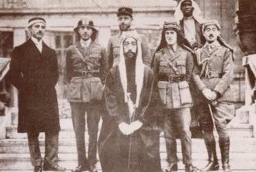 Délégation du Hedjaz à la conférence de Paix. À droite de Fayçal, Roustom Haïdar et Noury Saïd et à sa gauche T.E Lawrence. Derrière Fayçal, portant le képi français, le capitaine Rosario Pisani